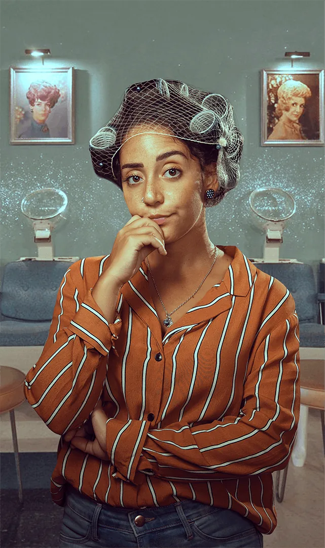 Woman under a vintage salon hair dryer wearing a hairnet with curlers